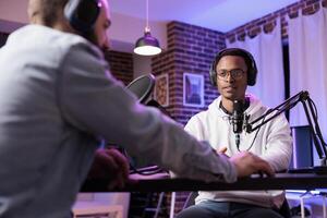 Podcast presenter having live discussion with man, streaming it for audience on internet entertainment show. Influencer enjoying chat with guest, broadcasting in personal home studio photo