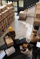 Stockroom team standing at counter desk in storage room, preparing customer order for delivery. Diverse employees discussing merchandise quality control, working at inventory in warehouse photo