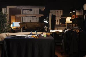 Table full of professional tailoring instruments used for manufacturing bespoke sartorial attire. Sewing machine, pins, needles, thread spools on table in atelier studio workspace photo