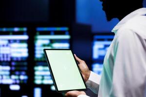 Manager examining server hub configuration settings using chroma key tablet. Supervisor meticulously analyzing event logs in monitoring software to pinpoint root cause of broken data center components photo