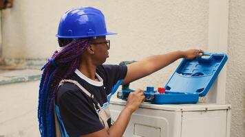 African american worker preparing for annual hvac system maintenance. Knowleadgeable engineer unpacking toolkit with professional instruments needed to clean clogged air filters restricting airflow photo