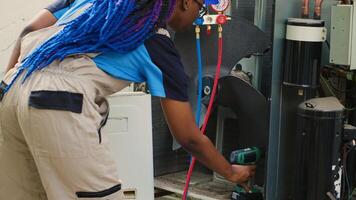 Portrait of happy technician starting work on busted air conditioner, using power tool to open up condenser and connect manometers. Engineer opening hvac system to start measuring freon levels inside photo