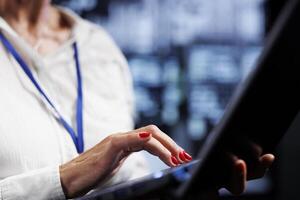 Efficient technician using laptop, ensuring valuable data remains shielded from potential security pitfalls, safeguarding server room devices against unauthorized access and vulnerabilities, close up photo