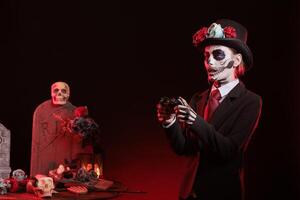 Woman playing videogames with controller in graveyard, celebrating Day of the Dead. Mysterious lady gaming with gamepad, surrounded by frightening funeral items during Halloween horror event photo