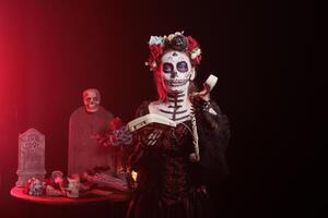 Woman talking on office cord telephone at Day of the Dead event to remember the deceased. Lady using landline phone to answer call during Mexican holiday of remembrance for those who have passed photo