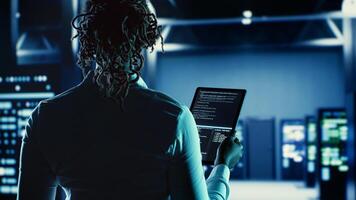 Knowledgeable woman running code on tablet, troubleshooting and upgrading high tech establishment equipment designed to accommodate supercomputers, networking systems and storage arrays photo