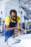 Engineer expertly examines car ignition system using advanced mechanical tools, ensuring optimal automotive performance and safety. Experienced garage employee conducts yearly vehicle checkup photo