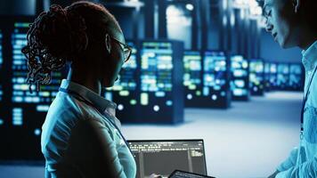 Adept african american technician programming scripts on tablet, updating data center infrastructure designed to accommodate modular servers, networking equipment and storage arrays photo