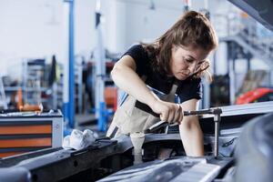Repair shop technician examines malfunctioning car battery using advanced mechanical tools, ensuring peak automotive performance. Employee in garage workspace conducts routine vehicle checkup photo