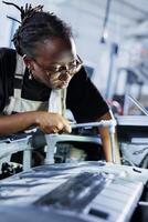 African american engineer does client car maintenance in auto repair shop after her vehicle shut down unexpectedly. Certified worker in garage mending customer damaged automobile fuel tank photo