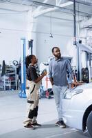 Specialist in repair shop using AR technology to show man car maintenance parameters. Garage worker using futuristic vr headset to inform client of what errors his vehicle is facing photo