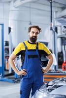 Portrait of proud serviceman in auto repair shop tasked with fixing broken cars. Knowledgeable specialist in garage ready to start doing checkups on automobiles in garage workspace photo