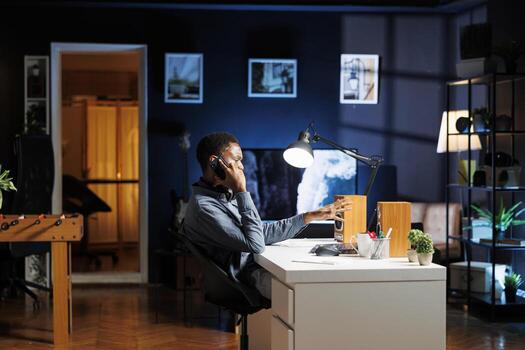 Financial advisor talks to his team on phone call at home, trying to obtain new business funding from shareholders. Young man doing remote work to increase revenue and reduce cost. photo