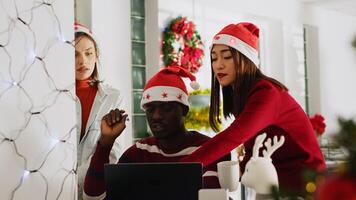 African american supervisor in Christmas ornate office delegating tasks to employees before winter holiday season. Manager showing workers expected project results on computer in xmas adorn workspace photo