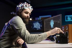 Man wearing EEG headset inserting disk into PC containing software turning AI into sentient being, saluting creator. Engineer placing cartridge in computer, awakening friendly artificial intelligence photo