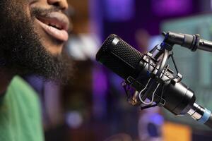 Songwriter musician composing a new track and recording it on microphone, singing aloud in his home studio and editing. Producer performing a song, acoustical engineering. Close up. photo