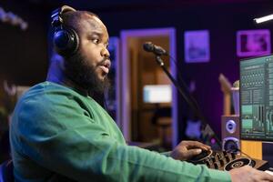 Talented musician mixing and mastering songs on a console, twisting pre amp knobs to add sound effects in post production. Producer composing new tracks for his album, working in home studio. photo