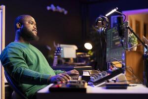Sound engineer playing piano and mixing tunes on digital software, composing new songs and adding audio effects in post production. Artist composer creating soundtracks for music industry. photo