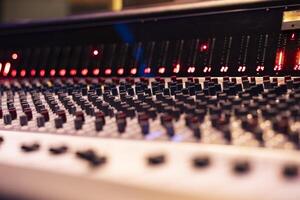 Mixing console and music production knobs in empty control room, technical gear used for recording and producing new tracks. Switchers, sliders and buttons editing audio files. Close up. photo