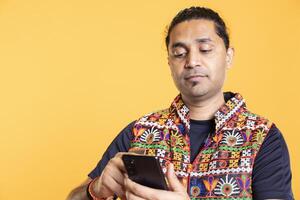 Indian customer adding payment method on website using smartphone, purchasing stuff, isolated over studio background. Man does internet shopping, typing debit card info on mobile phone photo