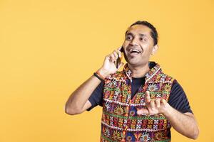 Cheerful man laughing at funny jokes with best friend over telephone call using smartphone. Person talking with hilarious mate in phone call using mobile phone, having fun, studio background photo