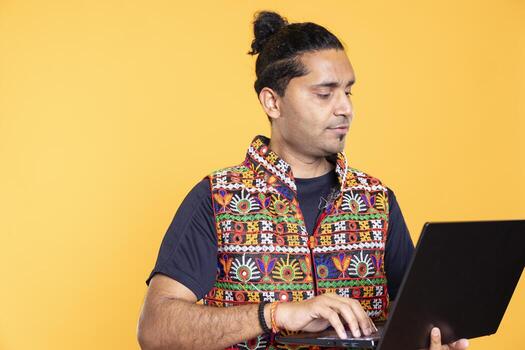 Indian man using laptop to do business related tasks for company, isolated over studio background. Office clerk doing budgeting, forecasting, and financial analysis on notebook photo