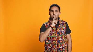 Authoritative man doing shushing hand gesturing, demanding secrecy, irritated by noise. Stern person complaining, placing finger on lips, doing quiet warning sign gesture, studio background, camera B photo