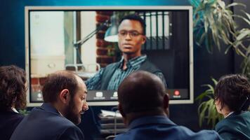 Team attends meeting with the business administrator to present a project briefing, addressing annual data reports and performance metrics via videocall conference online. Camera A. photo