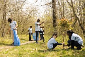 Diverse people working on reforestation and litter cleanup in the forest, fighting to restore natural environment. Group of activists joining community service activity, save the planet. photo