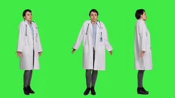 Physician being uncertain about something in studio, shrugging and feeling clueless about the right answer. Doctor doing i dont know symbol against greenscreen backdrop, confusion. Camera A. photo