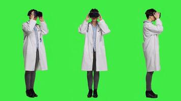 Physician uses virtual reality interactive lens on headset in studio, checks diagnosis with artificial intelligence three dimensional tool. Doctor works with vr glasses against greenscreen. Camera A. photo