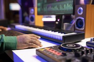 Sound designer operates on mixing console and digital software to edit audio files, adjusting volume levels with pre amp knobs in home studio. Technician produces new music on stereo gear. Close up. photo