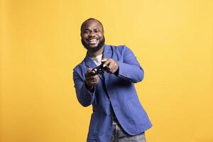 Portrait of jolly man man laughing while playing videogames with controller, having fun, studio background. African american gamer entertained by participating in online multiplayer game photo