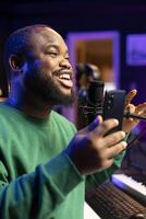 Composer songwriter performing acoustics for his new song in home studio, editing the tunes with mixing console. Artist musician recording tracks on microphone, creative melodic elements. Close up. photo