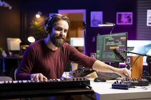 Portrait of male singer playing electronic keyboard notes and adding them on new soundtrack, using daw software to edit songs. Composer songwriter creating music with synthesizer keys. photo