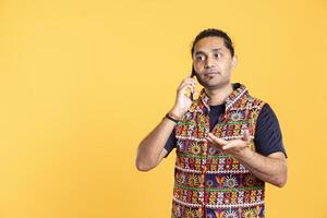 Confused indian man disagreeing with friend over debacle on call, feeling negatively surprised, studio backdrop. Perplexed person in disagreement with mate, being opposed to his arguments photo