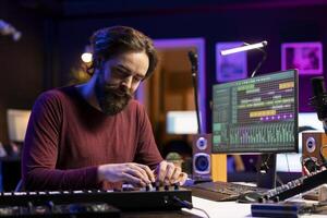 Young artist recording piano synthesizer notes and editing on a mixing console in his home studio. Skilled musician composer adjusting volume levels, equalization instruments and tools. photo
