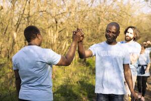 Group of environmentalists doing high five after a job well done, congratulating and giving praise to each other. Satisfied happy activists enjoying their successful activity. photo