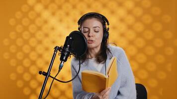 Voice actor reading book, recording for audiobook production using microphone and headset, studio background. Person using mic and headphones to produce digital recording of novel, camera B photo