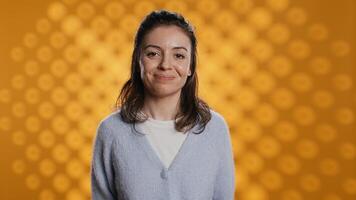 Portrait of upbeat optimistic woman posing, feeling happy and relaxed, isolated over yellow studio background. Close up shot of lively radiant caucasian lady standing, camera B photo