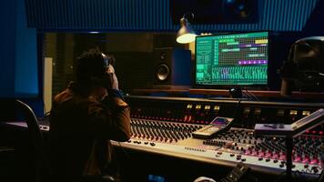 African american sound designer removing tonal imbalances and white noise on recorded files, music industry post production in professional studio. Control room expert editing tracks. Camera B. photo