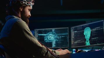 IT admin coding and using EEG headset to upload brain into computer, gaining immortality. Neuroscientist engineering transhumanism experiment, inserting consciousness into cyberspace, camera B photo