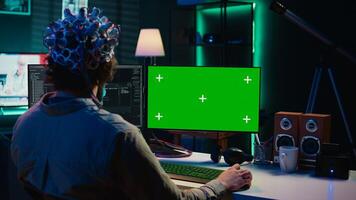IT admin coding and using EEG headset to upload brain into mockup computer, gaining immortality. Neuroscientist engineering transhumanism experiment on isolated screen PC, camera B photo
