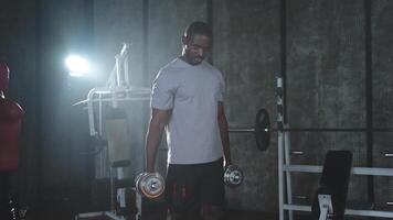Fitness trainieren im Fitnessstudio. afrikanisch amerikanisch Mann Bodybuilder pflücken oben Hanteln im Fitnessstudio. trainieren Gewicht Ausbildung Bizeps Muskeln mit Hantel im Fitness Verein. Mann tun Sport Übung. gesund Lebensstil video