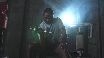 Fitness trainieren im Fitnessstudio. afrikanisch amerikanisch Mann Bodybuilder pflücken oben Hanteln im Fitnessstudio. trainieren Gewicht Ausbildung Bizeps Muskeln mit Hantel im Fitness Verein. Mann tun Sport Übung. gesund Lebensstil video