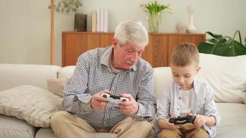 Happy family. Old senior man grandfather boy grandson playing game with joysticks at home. Smiling grandparent and child using gamepads for game. Older generation modern tech usage video