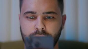 Close up face Caucasian man play gaming addict glued mobile phone smartphone cellphone digital device guy male tech watching network cyberspace wireless social web bedroom bed night user connect video