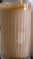 Chocolate milk pouring into a glass, splashing as it flows over, spilling on the table video