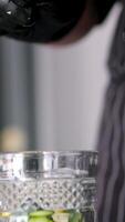 Add lemon to glass. Making lemonade, summer drink, cold drink, healthy liquid. Throw a slice of lemon into a glass Forceps throw lemon water glass closeup. Cold water with fruit slice video