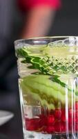 Preparation of a refreshing summer drink - lemonade from grapefruit, lemon, mint, red currant, ice with syrup and water. Woman chef preparing in the kitchen, close-up video